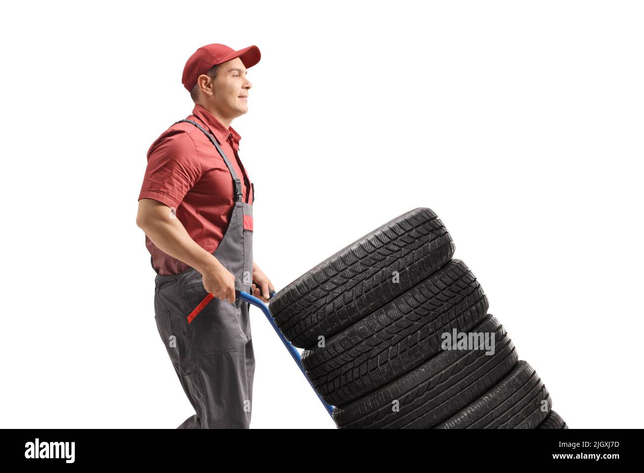 Man pushing car tires with a hand truck isolated on white background Stock Photo