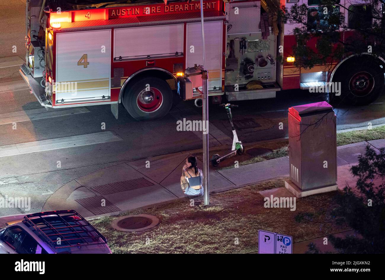 Austin Texas USA, July 2022: A woman sits on the sidewalk in the aftermath of a car accident at the corner of 12th and Guadalupe downtown where one man was transported to the hospital. Circumstances about the accident and the woman's involvement in the situation are unknown.  ©Bob Daemmrich Stock Photo