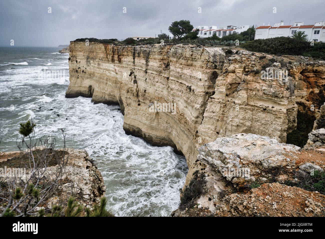 View from the mountain edge to the rocky coastline, moody sky, raging Atlantic Ocean during stormy weather. Portugal, Europe Stock Photo