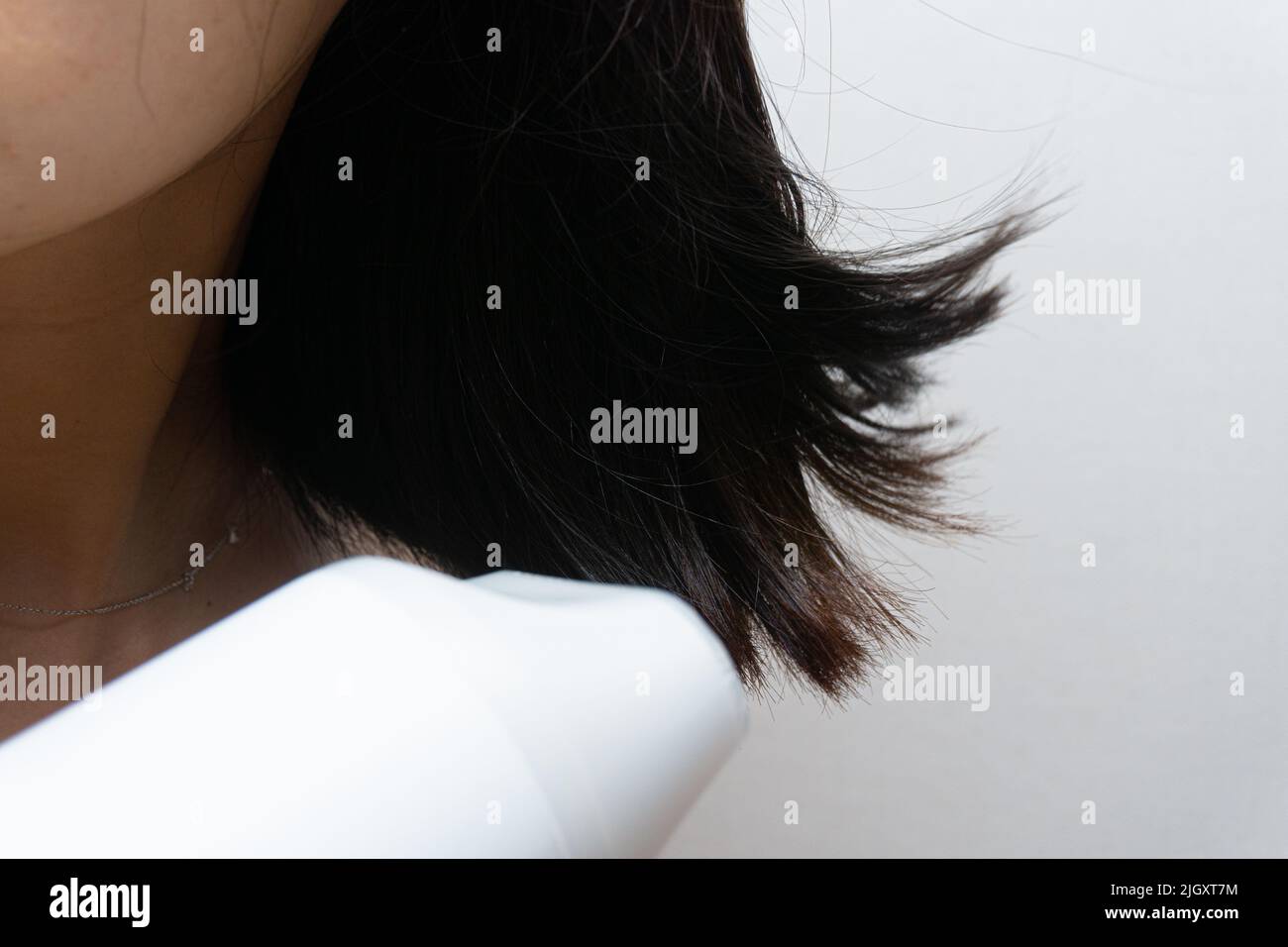A woman drying her hair with a hair dryer Stock Photo - Alamy