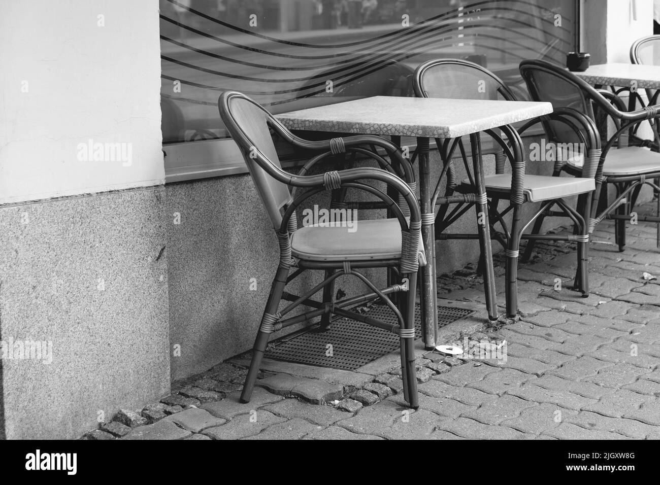 empty seats in front of a street cafe in a city in black and white Stock Photo