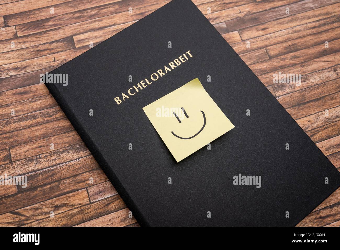 Adhesive note with a smiley on a Bachelorarbeit (bachelor thesis). Printed and bound thesis with a black cover. Finishing studies in Germany. Stock Photo