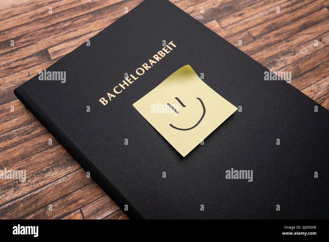 Adhesive note with a smiley on a Bachelorarbeit (bachelor thesis). Printed and bound thesis with a black cover. Finishing studies in Germany. Stock Photo