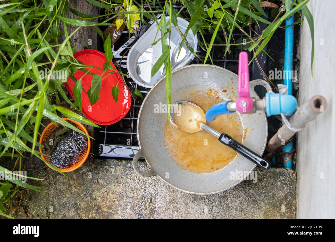 An unwashed dishes under the pipe with tap in the rural backyard Stock Photo
