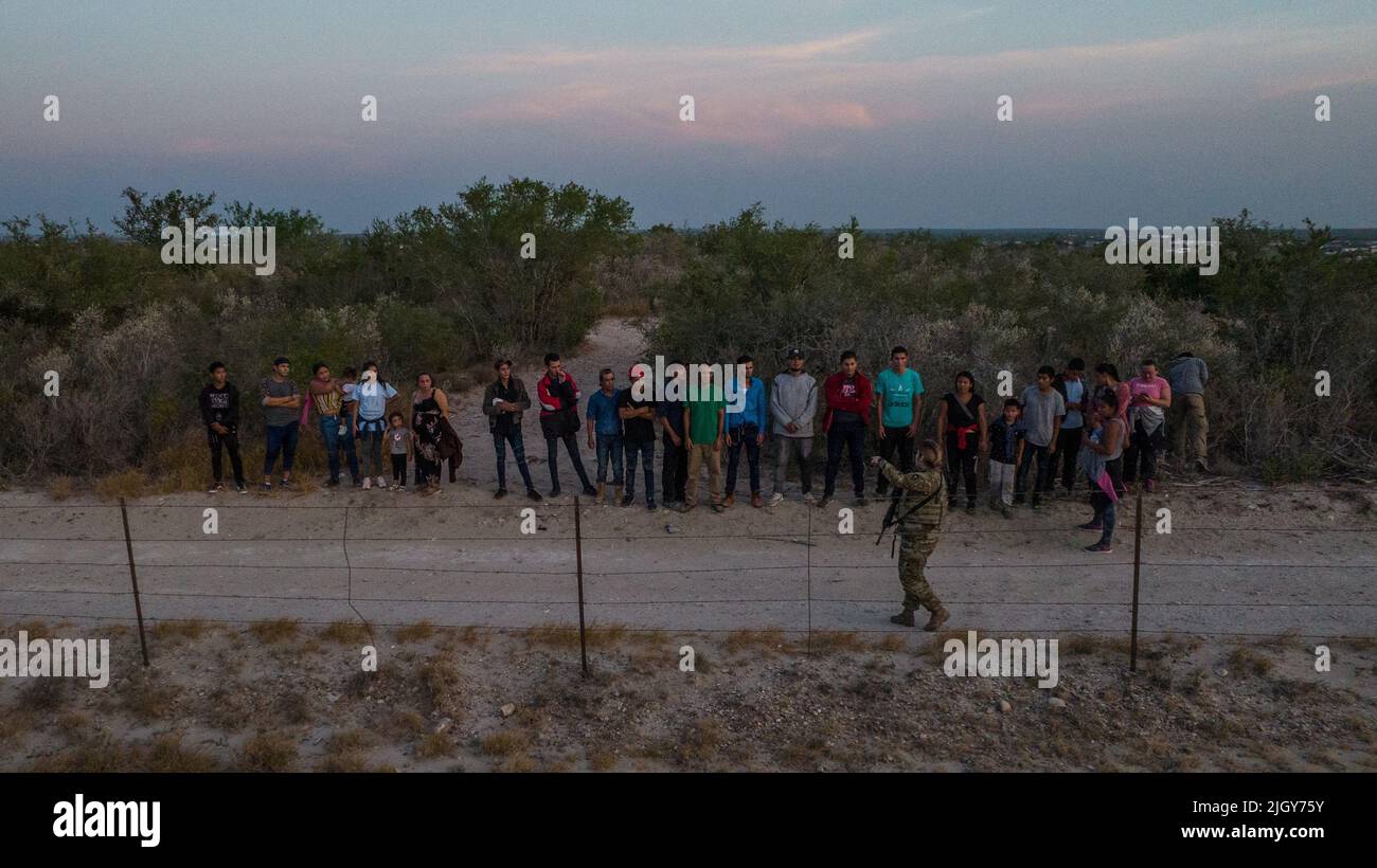 A member of the Texas Army National Guard directs migrants from Central and South America after they were smuggled across the Rio Grande river into the United States from Mexico in Roma Creek, Texas, U.S., July 12, 2022.  REUTERS/Adrees Latif Stock Photo
