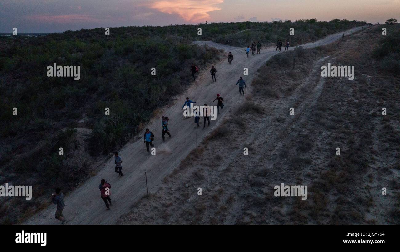 Migrants from Central and South America walk along a dirt trail after they were smuggled across the Rio Grande river into the United States from Mexico in Roma Creek, Texas, U.S., July 12, 2022. REUTERS/Adrees Latif Stock Photo