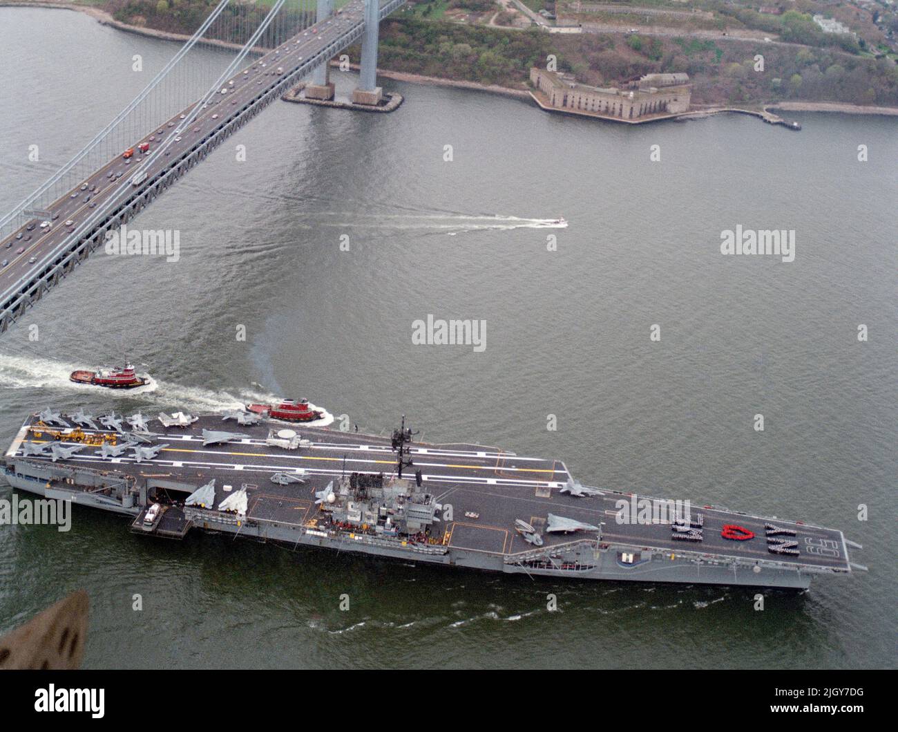 The aircraft carrier USS FORRESTAL (CV 59), escorted by a pair of tug boats, passes under the Verrazano Narrows Bridge as it approaches New York City. The FORRESTAL and its battle group as visiting the city for Fleet Week'89 Stock Photo