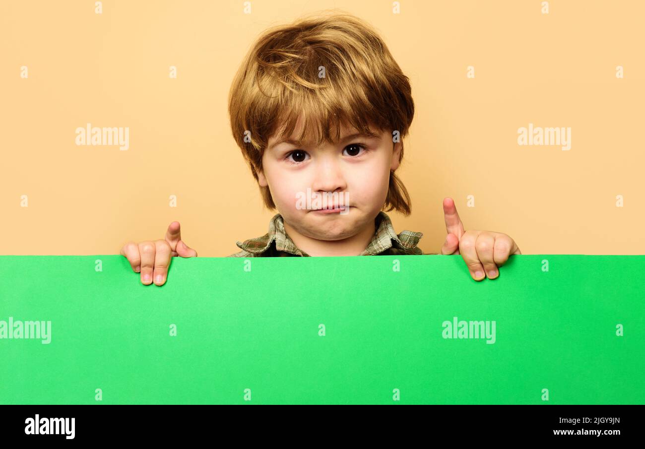Child boy with empty billboard. Little kid with blank sign board. Advertising of childrens goods. Stock Photo