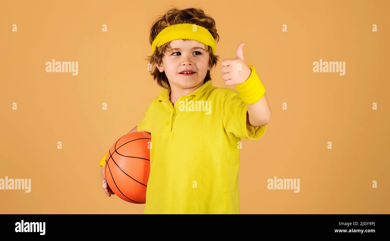 Sporty boy in sportswear with basketball ball shows thumb up. Sport for children. Healthy lifestyle. Stock Photo