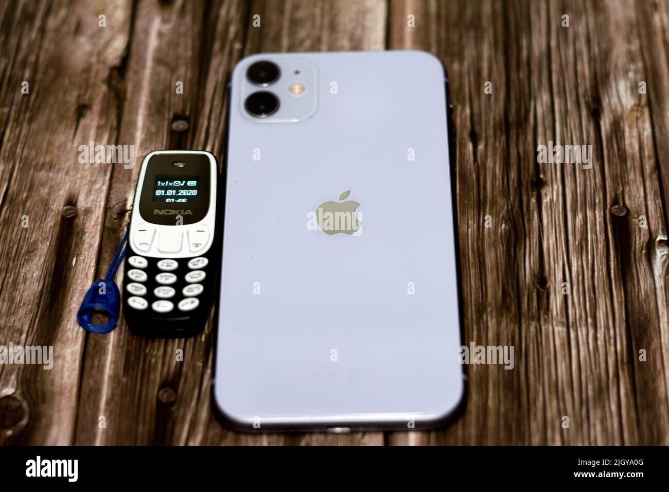 Cairo, Egypt, June 11 2022: Apple iPhone 11 with 6.1inch Liquid Retina HD High definition display and a tiny small old mini Nokia cell phone with a ke Stock Photo