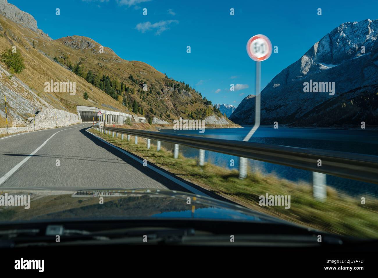 Car moving fast with speed limit violation on a twisty road with a rocky landscape. View from the interior of a vehicle. Dangerous driving concept. Stock Photo