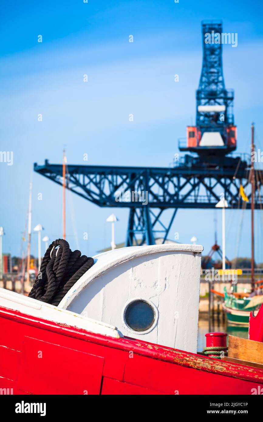 Part of old wooden trawler boat with cabin porthole and crane steel construction at background sky (copy space) Stock Photo