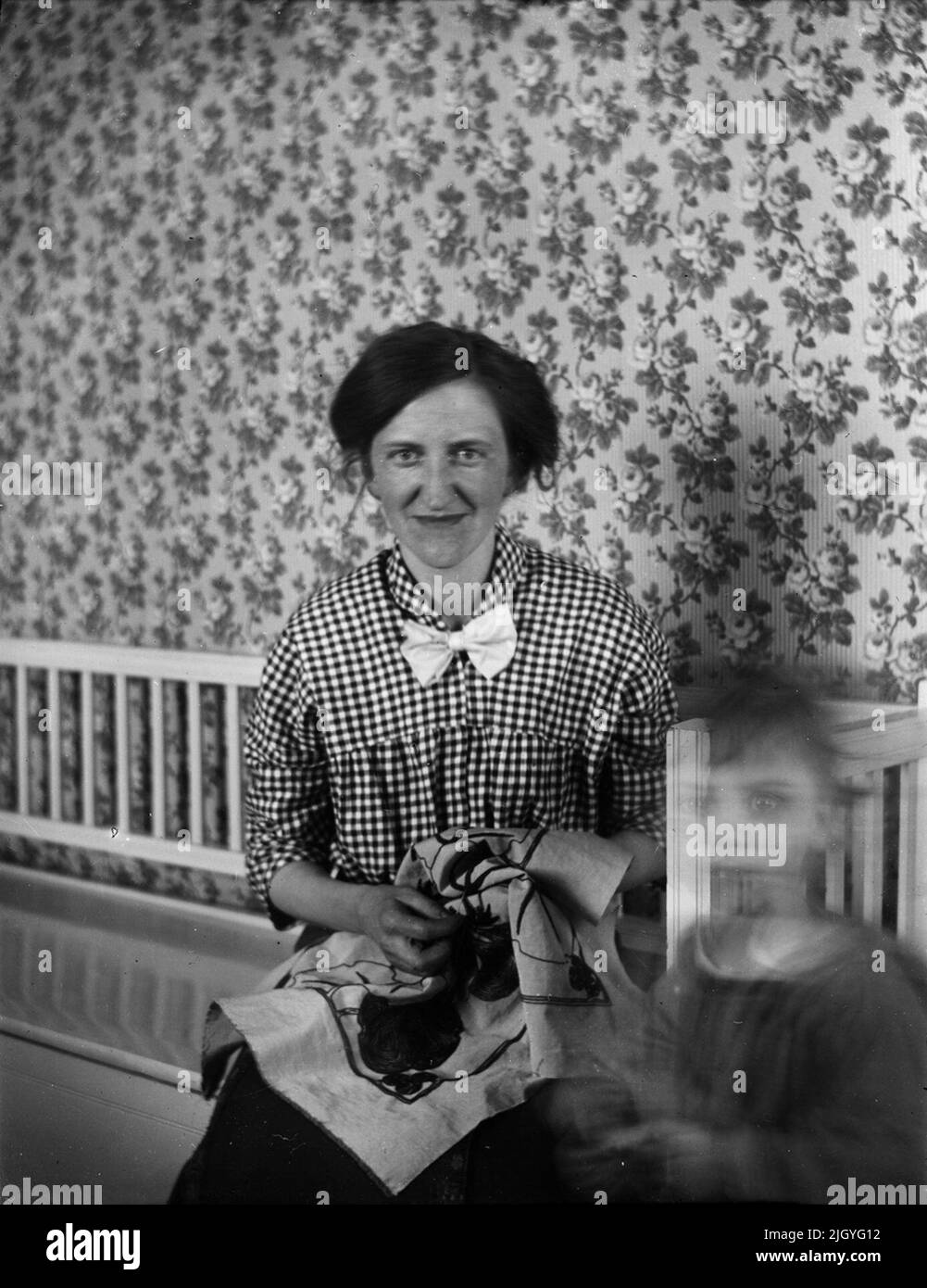 Nora Ärnström with embroidery work. To the right, a child who does not want to be still. Josef Ärnström's image collection was acquired by the Upplands Museum 2011.josef Ärnström was born in 1887 in Keep, Hållnäs parish, Uppland. He was married to Nora Selldin, born in Timrå, Medelpad. Both Josef and his wife Nora took their degrees around 1910 at the teacher's seminar in Uppsala. In Medelpad, the couple received their first teacher services at Berge school as a newlyweds about 1910-12. The relocation then moved on to Lapland where Josef was employed in Toulleuvaara between about 1913-18. Jose Stock Photo