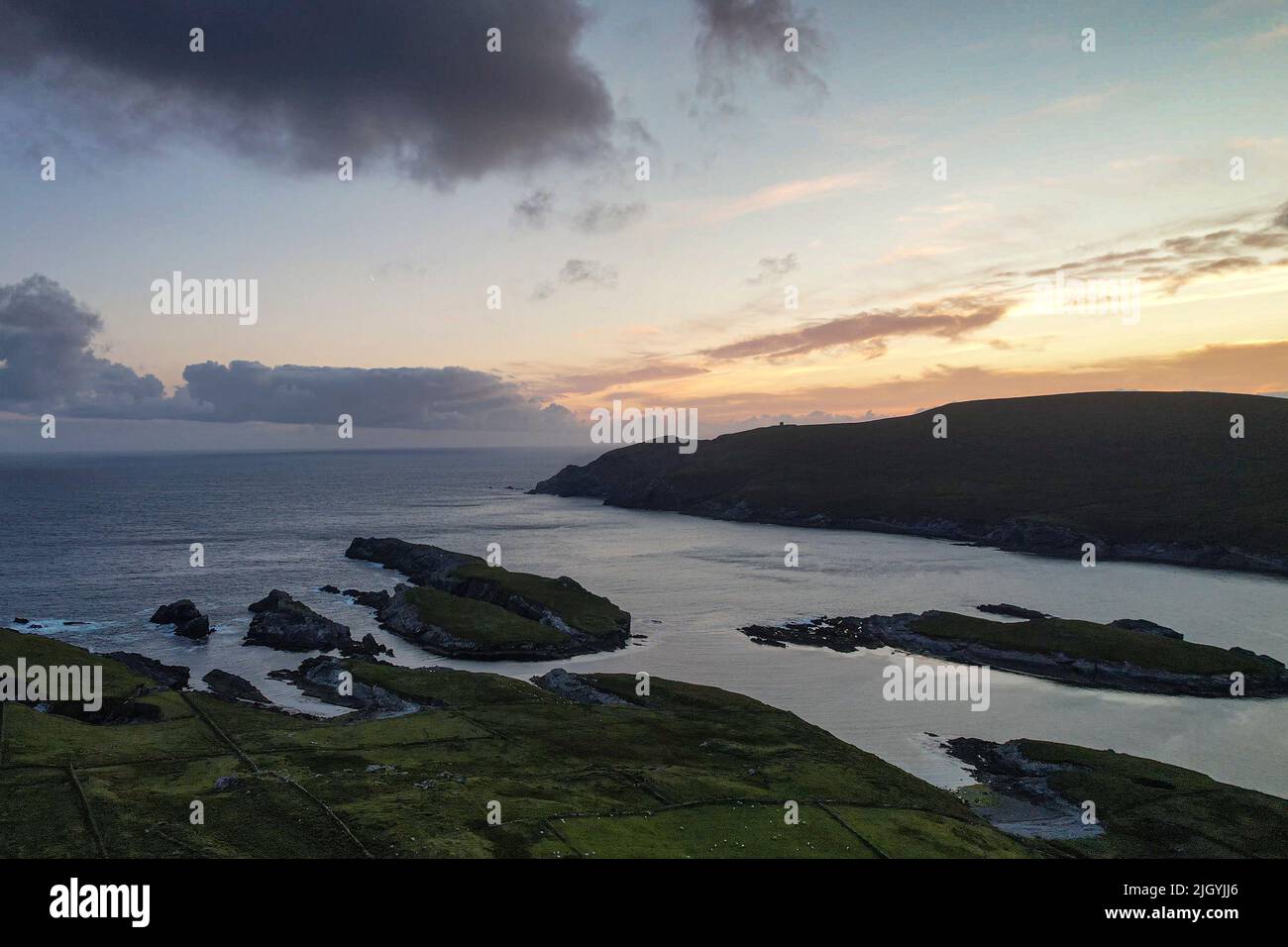 Wednesday 13th July 2022. Portmagee and Valentia Island, County Kerry, Ireland. A warm low from the sky as sunset falls over Bray Head, Valentia Island and Portmagee Bay, County Kerry, Ireland. Photo Credit: Stephen Power / Alamy Live News Stock Photo