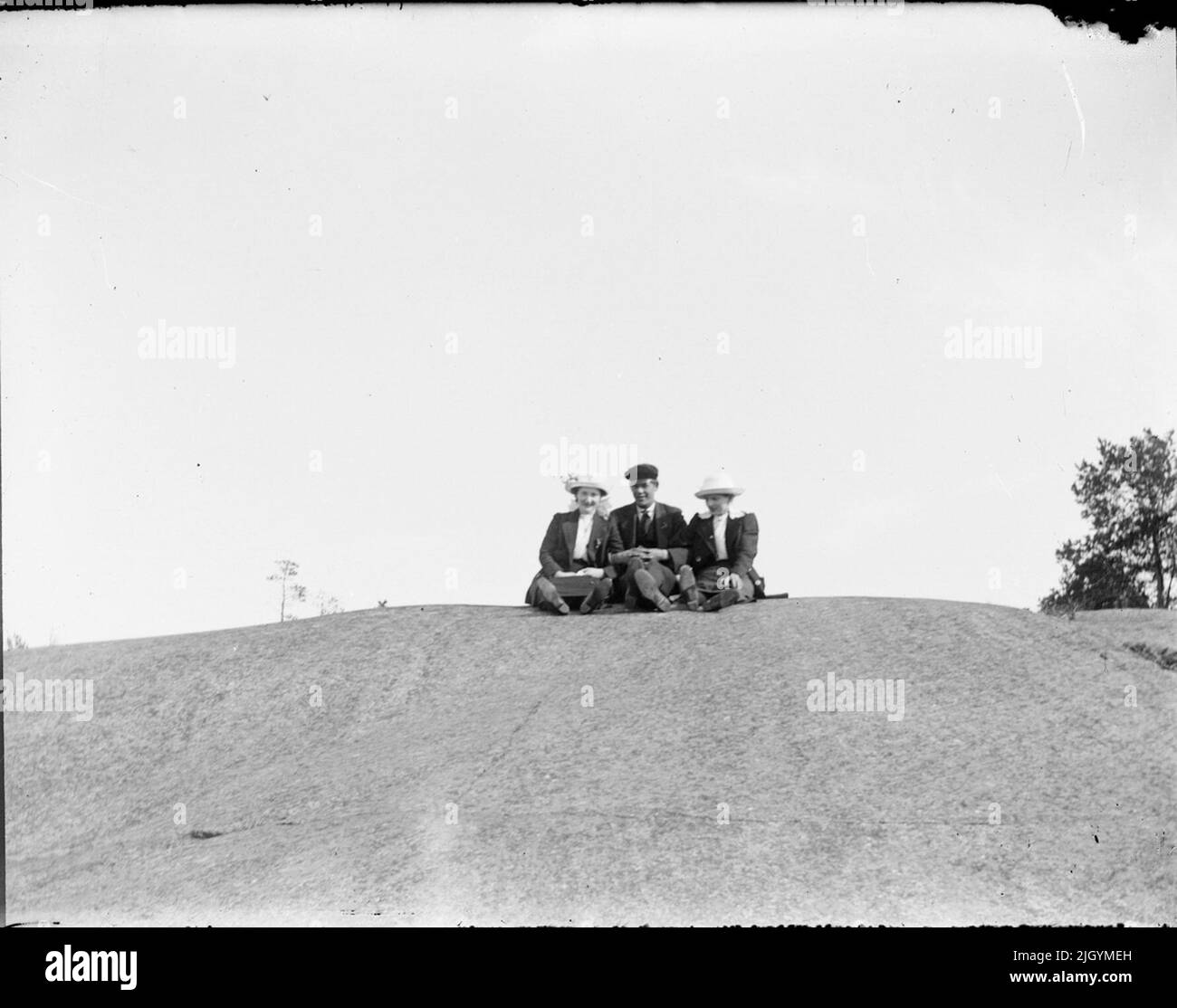 Two women and one man sits on a hill, Östhammar, Uppland. Two women and one man sits on a hill, Östhammar, Uppland Stock Photo