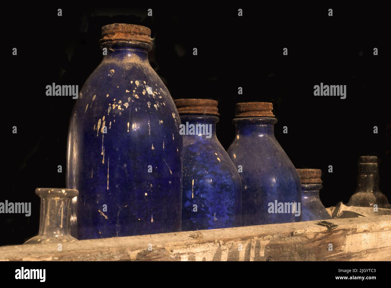 A collection of antique bottles sits with other items in the window of an abandoned store. Stock Photo