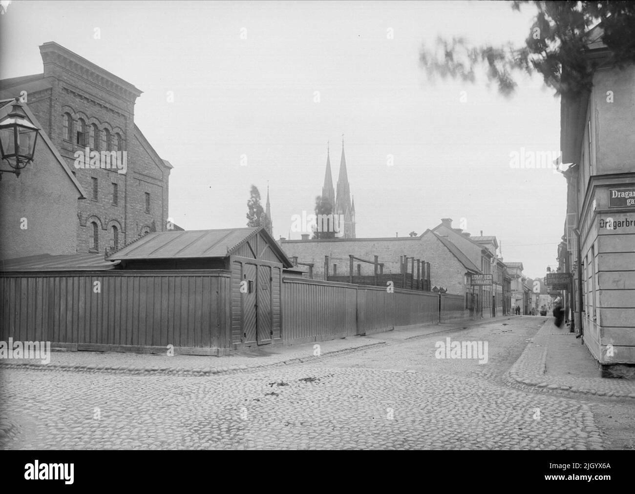 S: t Olofsgatan - Dragarbrunnsgatan in Uppsala 1901 - 1902 with Upsala Bavarian Brewery AB. Järnbrogatan (St. Olofsgatan) towards southwest from Dragarbrunnsgatan. Upsala Bavaria Bryggeri AB had a large farm against Järnbrogatan. The magazine on the left was built in 1881 according to the 1880 city plan. The building's gable to the street was therefore placed and designed given that it would be named against the broad esplanade that Järnbrogatan would be made according to the city plan. The implementation of the widening came to be delayed until the 1960s. 'From Ola Ehn & Gunnar Elfström, the Stock Photo