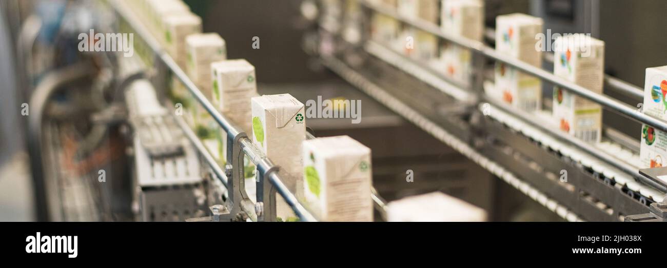 Conveyor at the plant for the production and bottling of juices in cardboard packaging. Web banner Stock Photo
