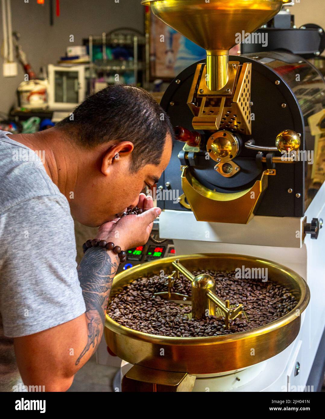 Mr. Thanh checks the coffee beans before taking the next step.  Coffee houses and cafes are very popular in Vietnam as a producer grower too. Stock Photo