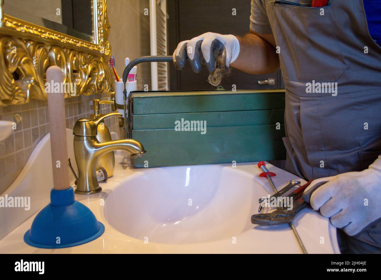 Image of the hands of a plumber in work gloves holding a lock of hair
