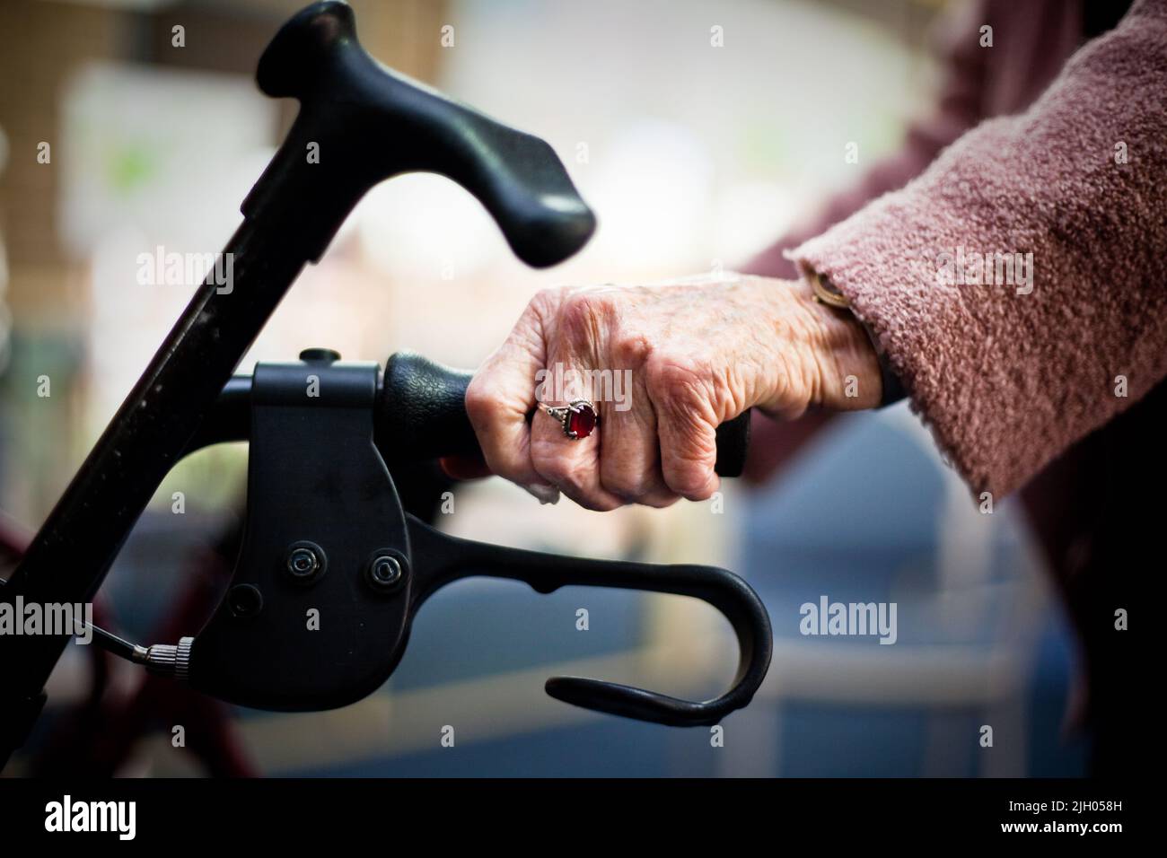 CLOSE-UP OF AN ELDERLY WOMAN'S HAND HOLDING ON TO A MOBILITY DEVICE. Stock Photo