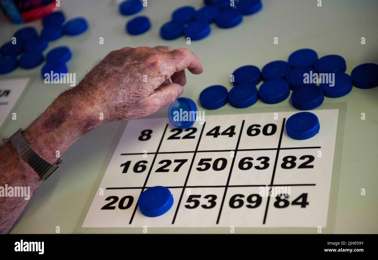 CLOSE UP OF THE HANDS OF AN ELDERLY PERSON IN AN AGED CARE HOME PLAYING BINGO. Stock Photo