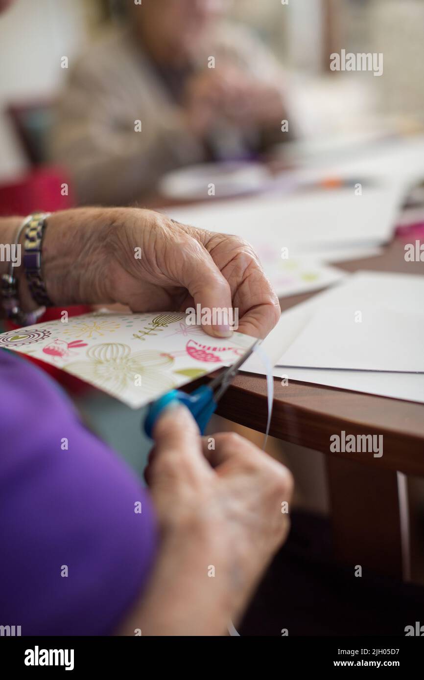 CLOSE UP OF  AN ELDERLY LADY IN AN AGED CARE HOME DOING CARD MAKING Stock Photo
