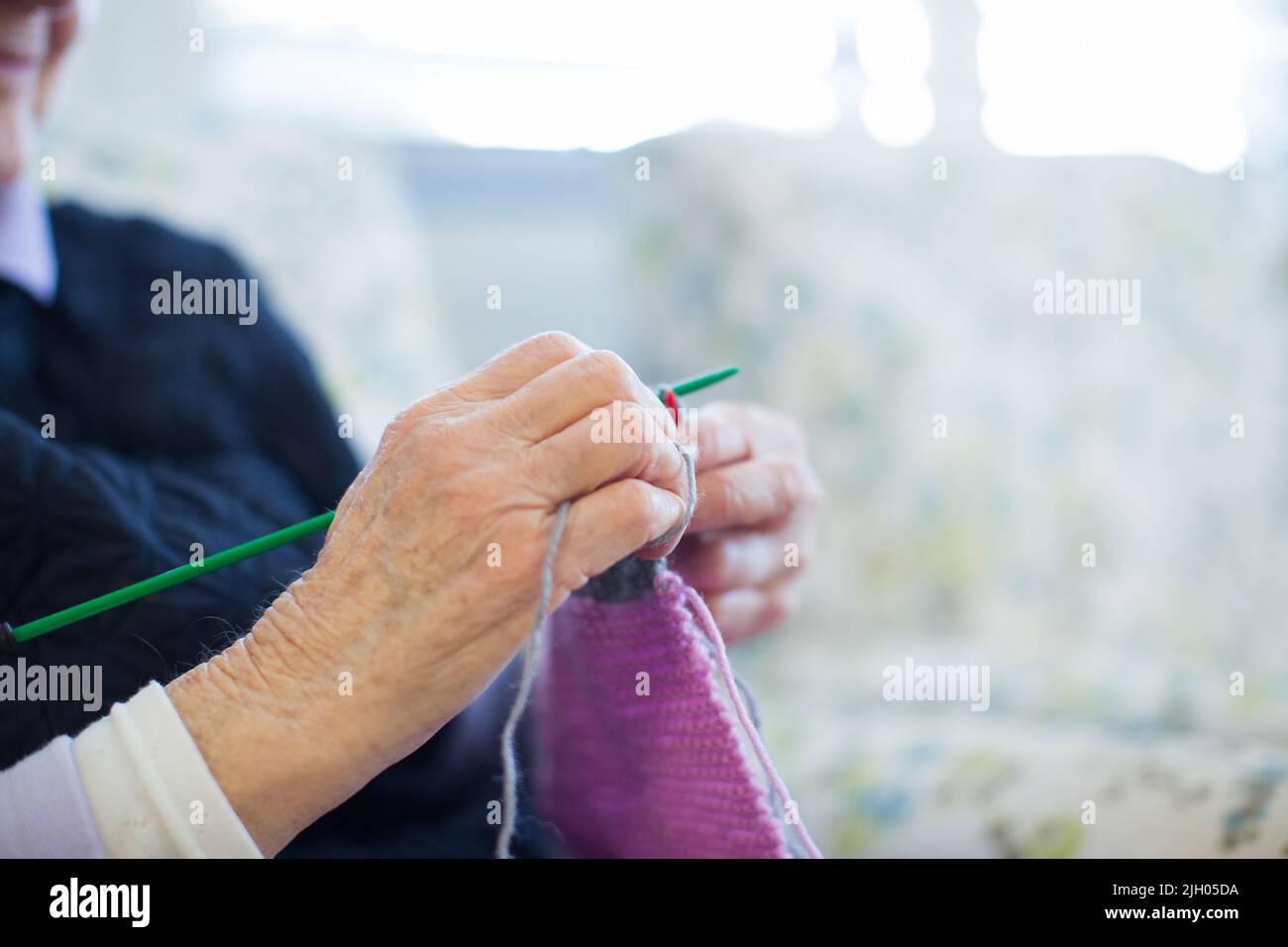 CLOSE UP OF THE HANDS OF AN ELDERLY LADY IN AN AGED CARE HOME KNITTING Stock Photo