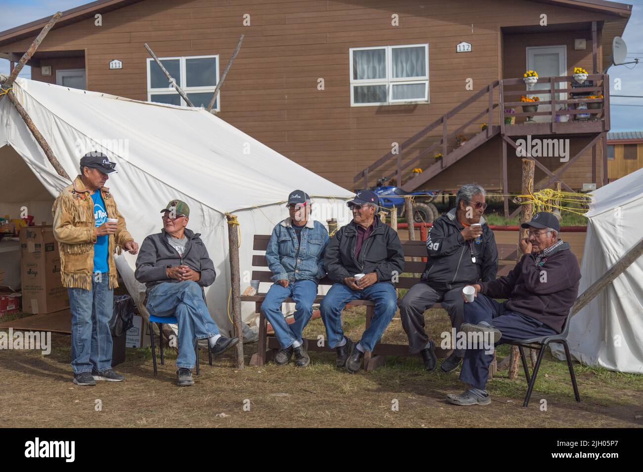 Indigenous Dene elder men sitting on bench, in the northern community of Deline, Northwest Territories, Canada Stock Photo