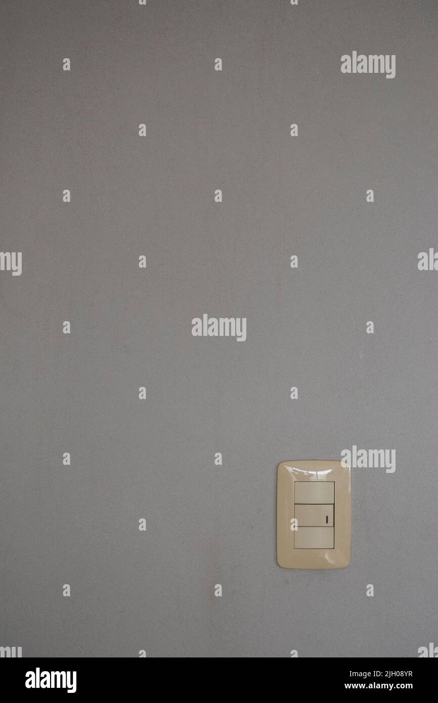 Title: White light switch on plain gray wall background Stock Photo