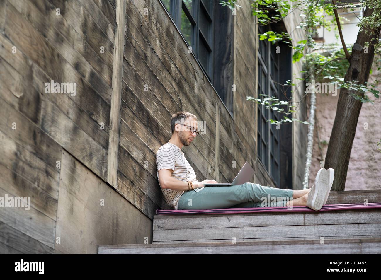 Smiling focused millennial man in casual using laptop computer calm open space workplace Stock Photo