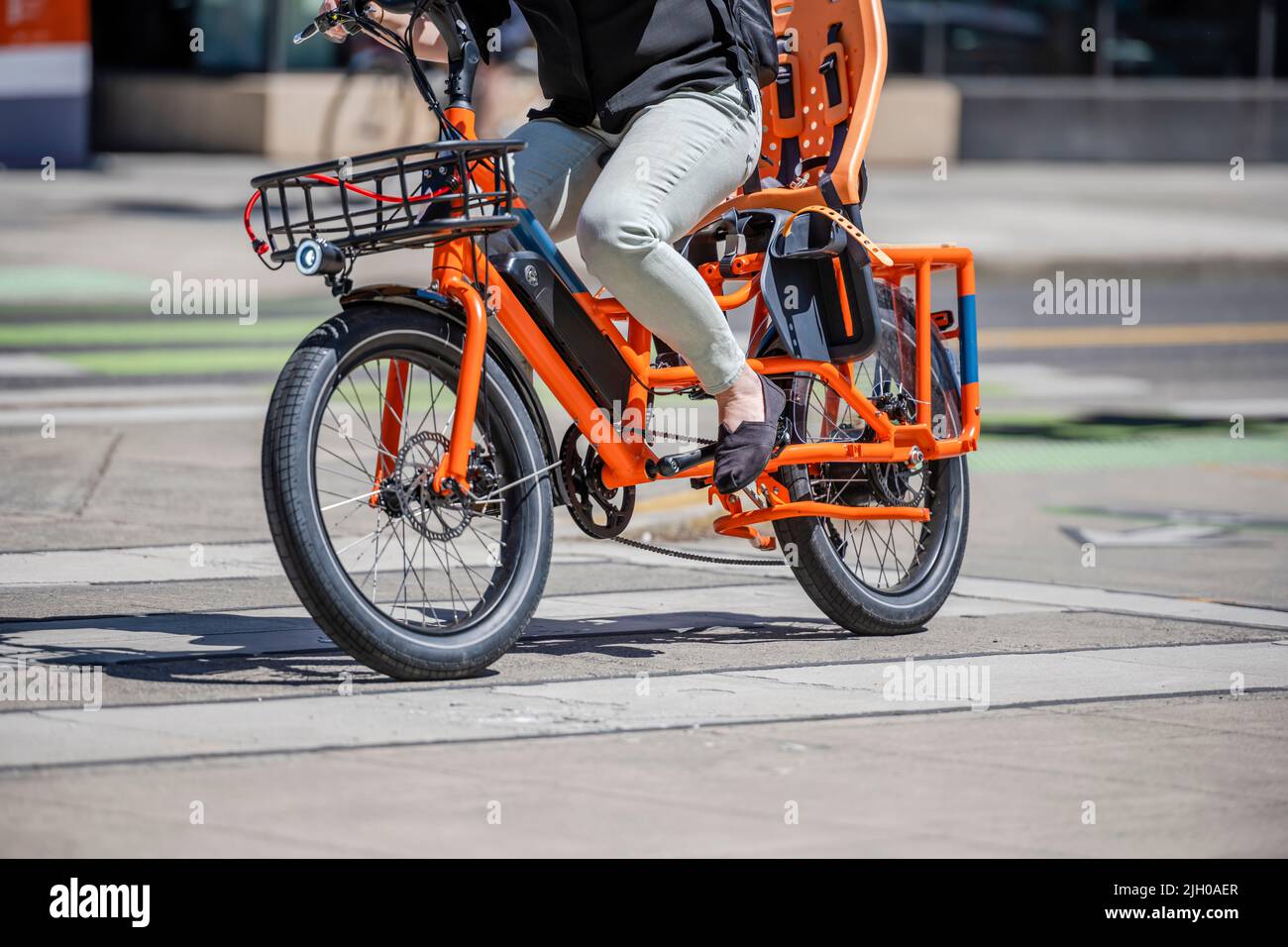 Woman on an electrical bike rides a bicycle along the city sidewalk