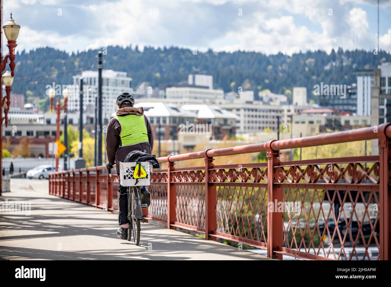 A man on a bike pedals a bicycle on a dedicated path for cyclists on the Broadway bridge preferring an active healthy lifestyle using cycling ride and Stock Photo