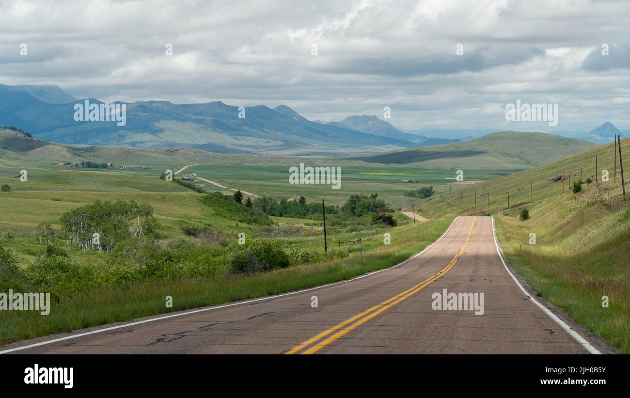 The two-lane road stretches off into the far distance in the hills of western Montana. Stock Photo