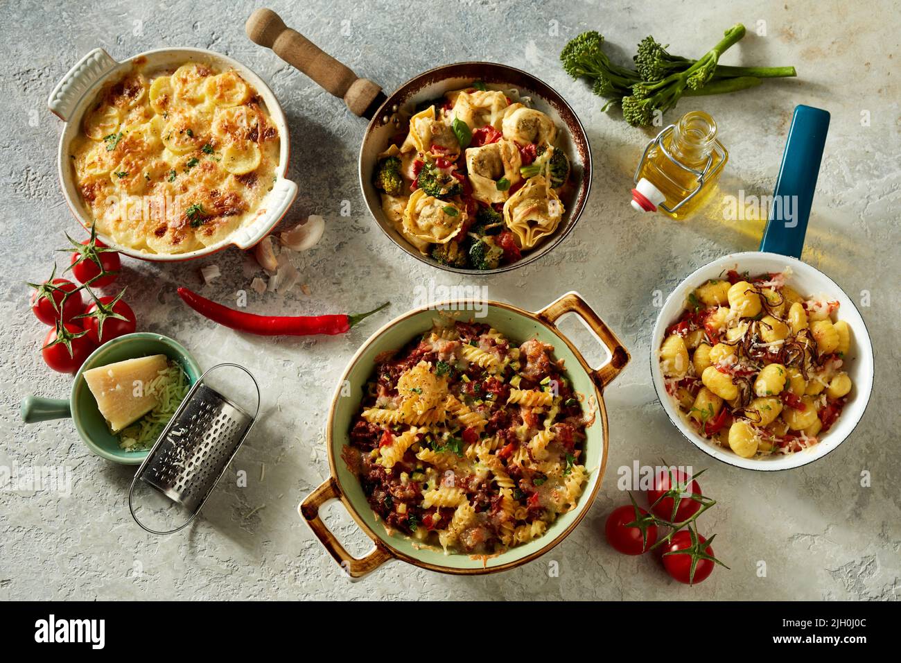 To view of tasty dishes of Italian cuisine in pans and casseroles placed with fresh ingredients on table Stock Photo