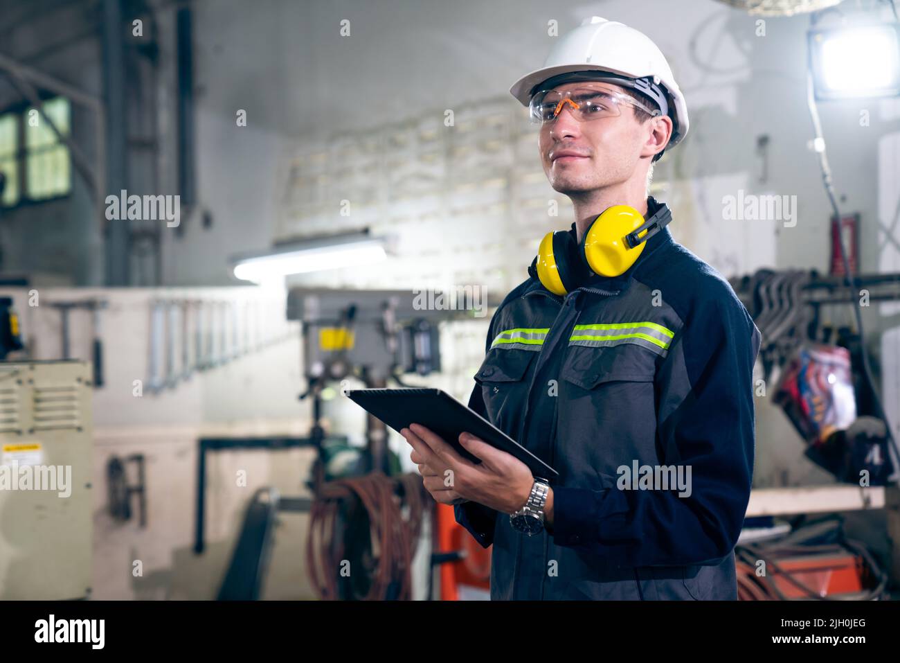Young factory worker using adept tablet computer in a building . Industrial technology