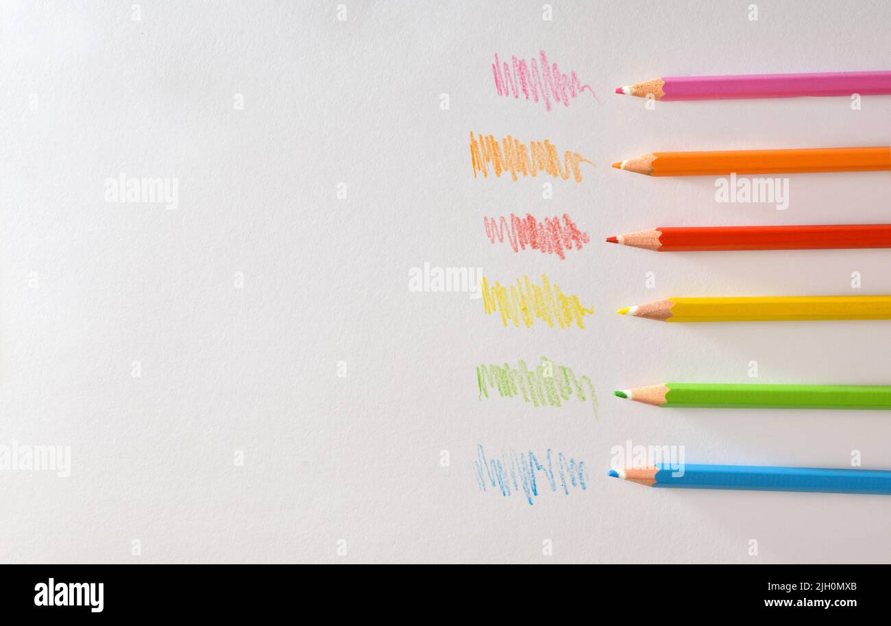 Various colored pencils on white striped paper. Top view. Horizontal composition. Stock Photo
