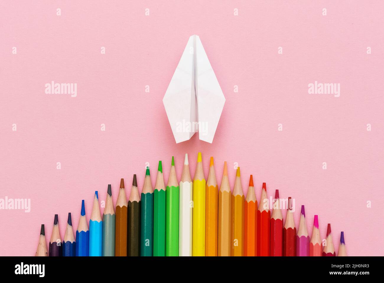 Paper plane, wood colored pencils, flat dip on pink background, top ...