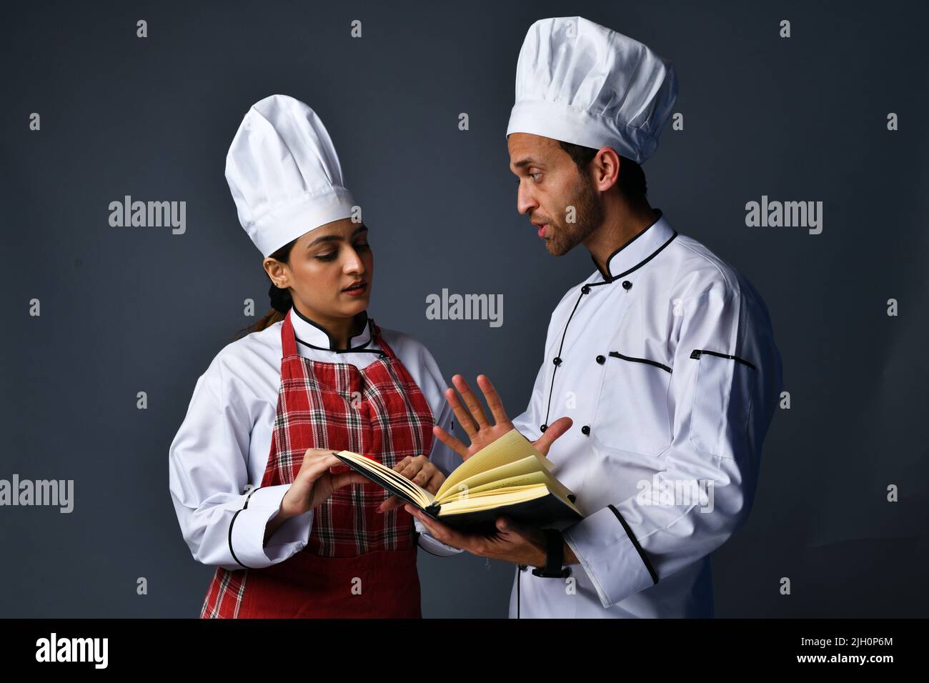 Male and female chefs are discussing about the recipe for cooking Stock ...
