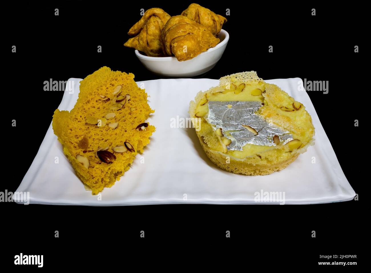 Khoya Ghevar or Malai Ghewar is Indian sweet made on Teej,Janmashtami,Raksha Bandhan in Rajasthan,Punjab,UP,India.Front view of ghewar,samosa. Stock Photo