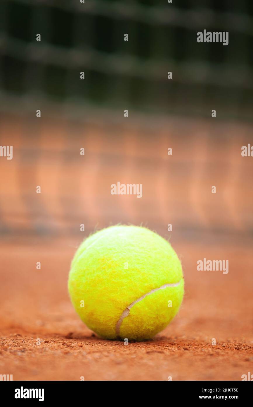 Yellow tennis ball lies on the clay court close up. Stock Photo