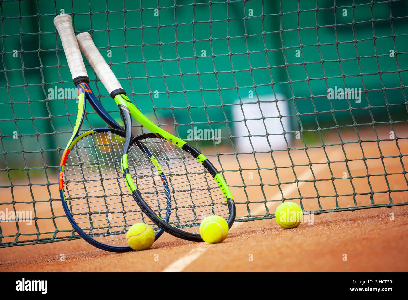 Two tennis rackets and balls leaned against the net Stock Photo Alamy
