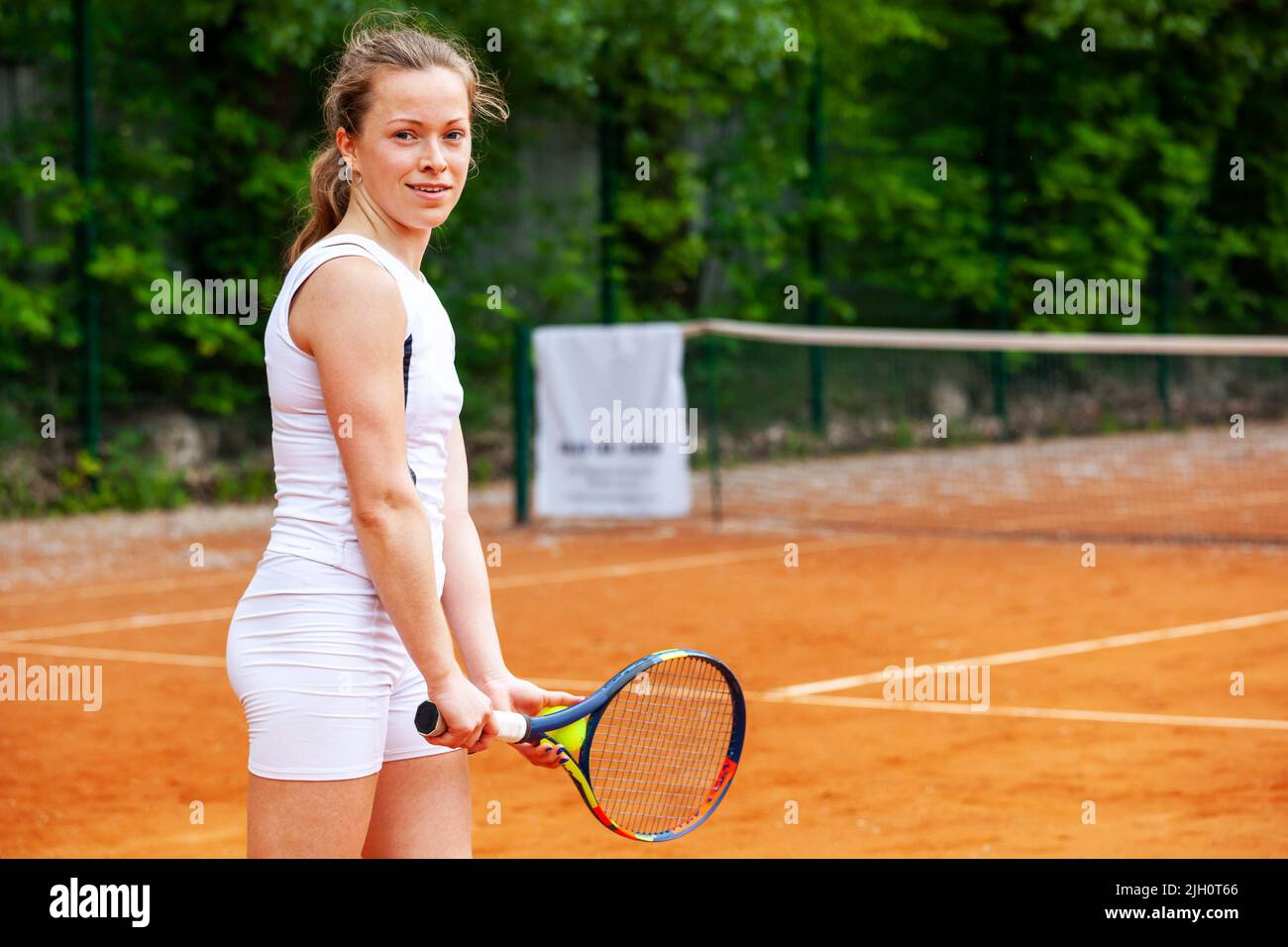 Happy female tennis player holding the racket in ready position. Stock Photo
