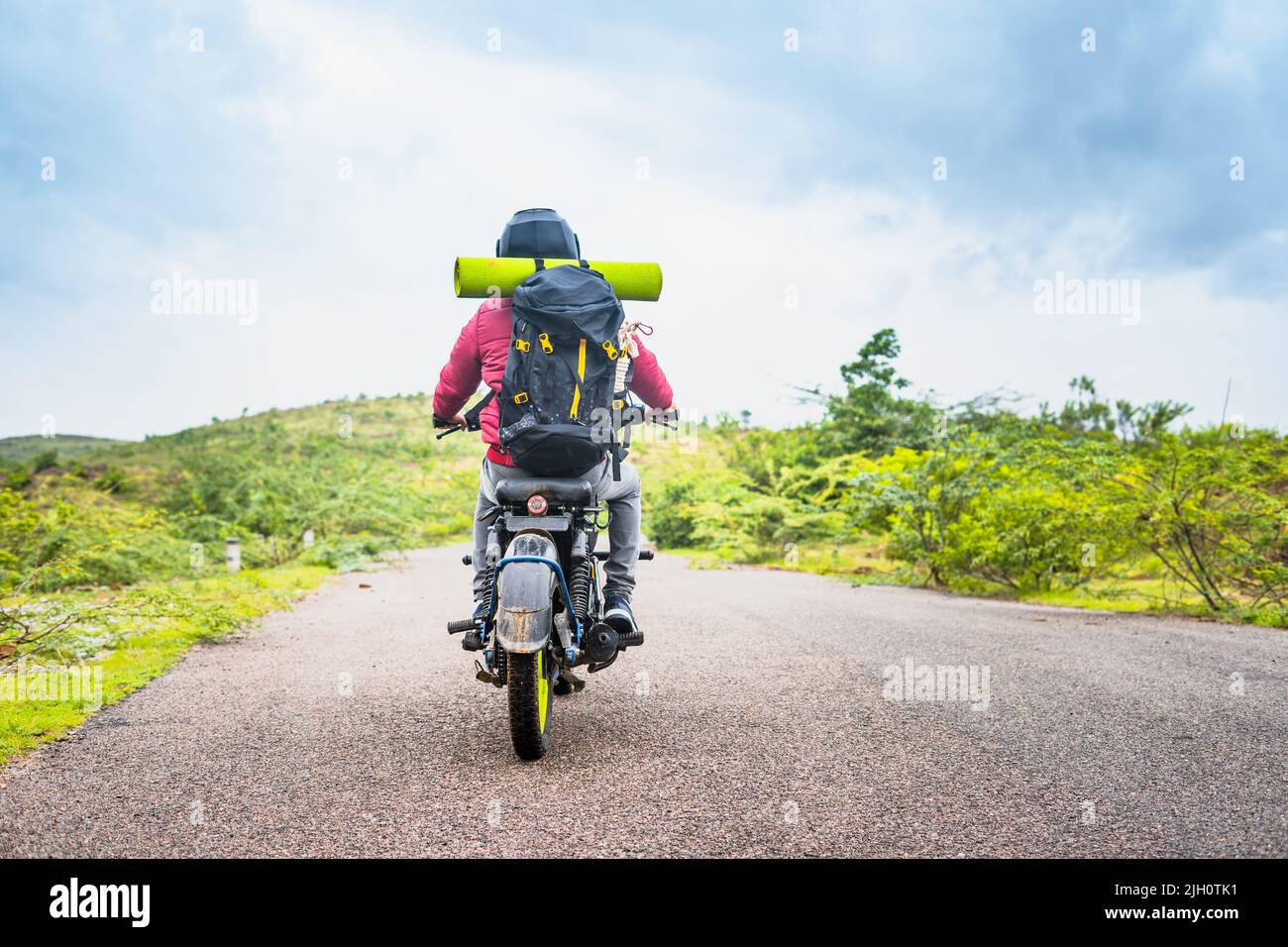 back view of man with backpack travelling motor bike near mountains - concpet of freedom, adventure and holidays Stock Photo