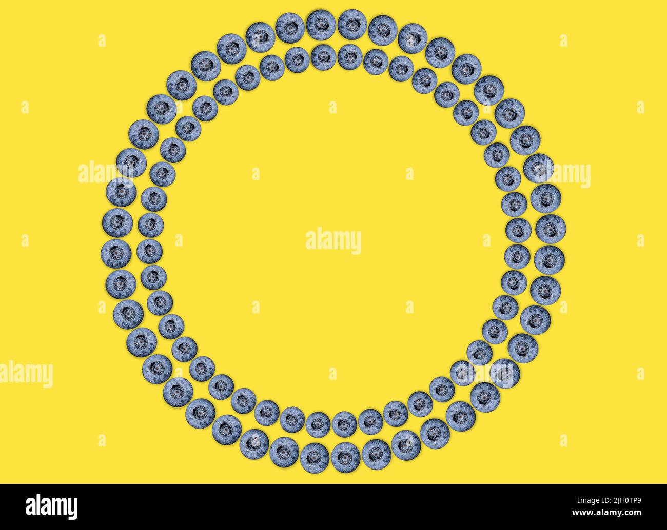 Fresh blueberries arranged into a circle frame isolated on yellow. Stock Photo