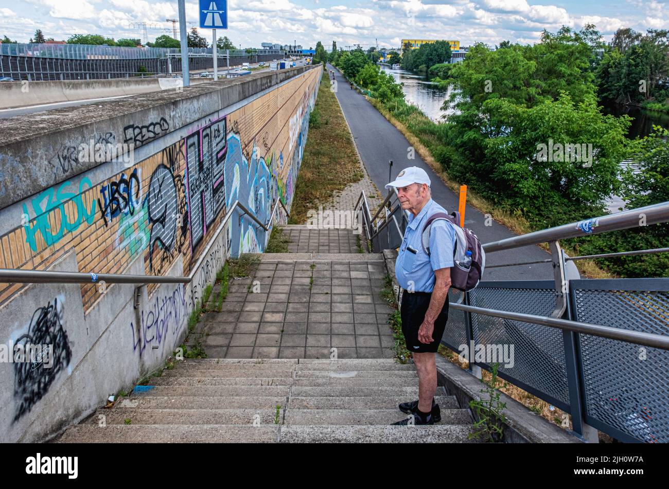 Senior elderly man on steps from Massantebrücke  Bridge to cycle path along Teltow canal - Johannisthal, Berlin, Germany. Stock Photo