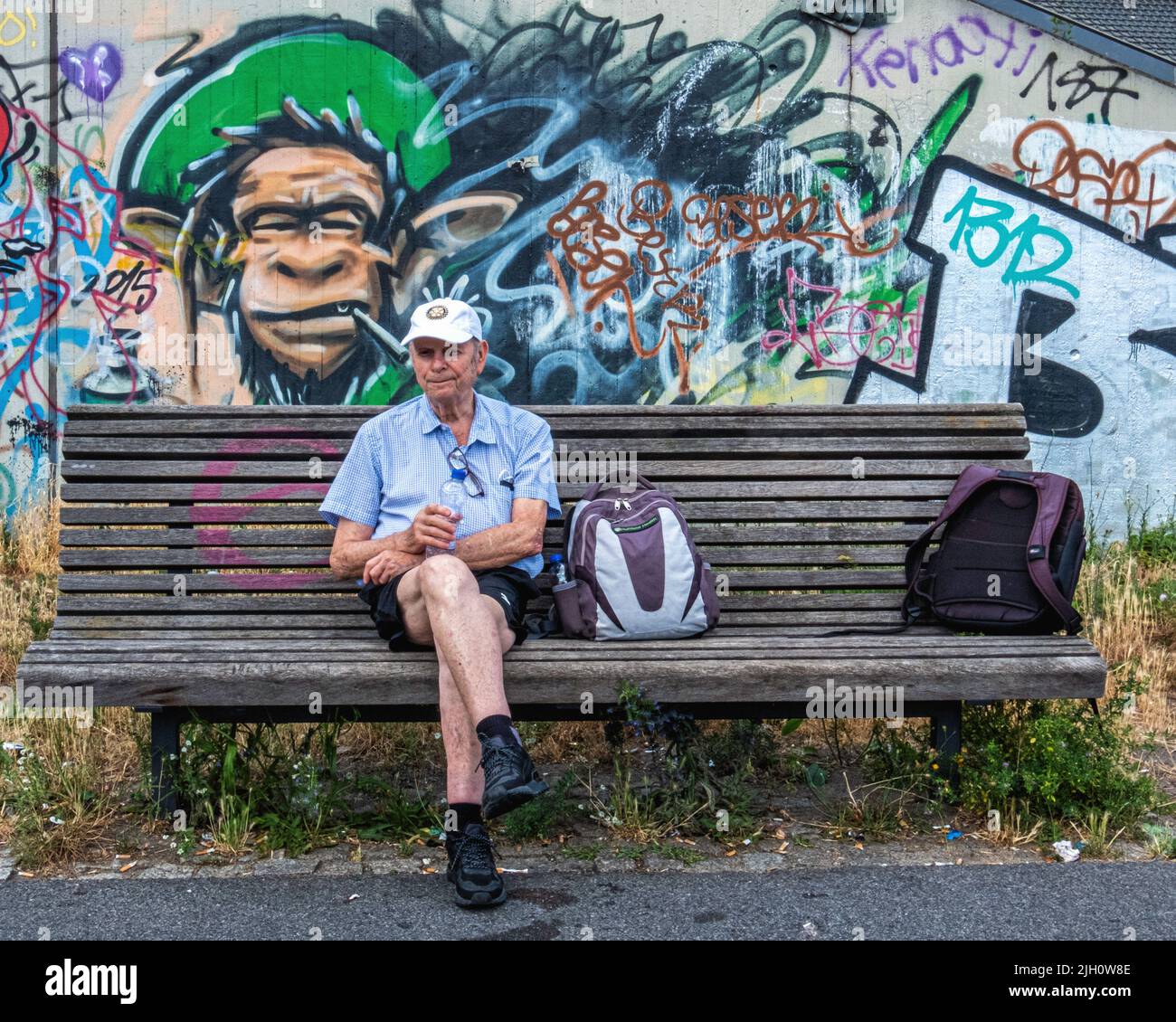 Senior elderly man taking a rest while walking the former Berlin wall trail along the Teltow canal - Johannisthal, Berlin, Germany. Stock Photo