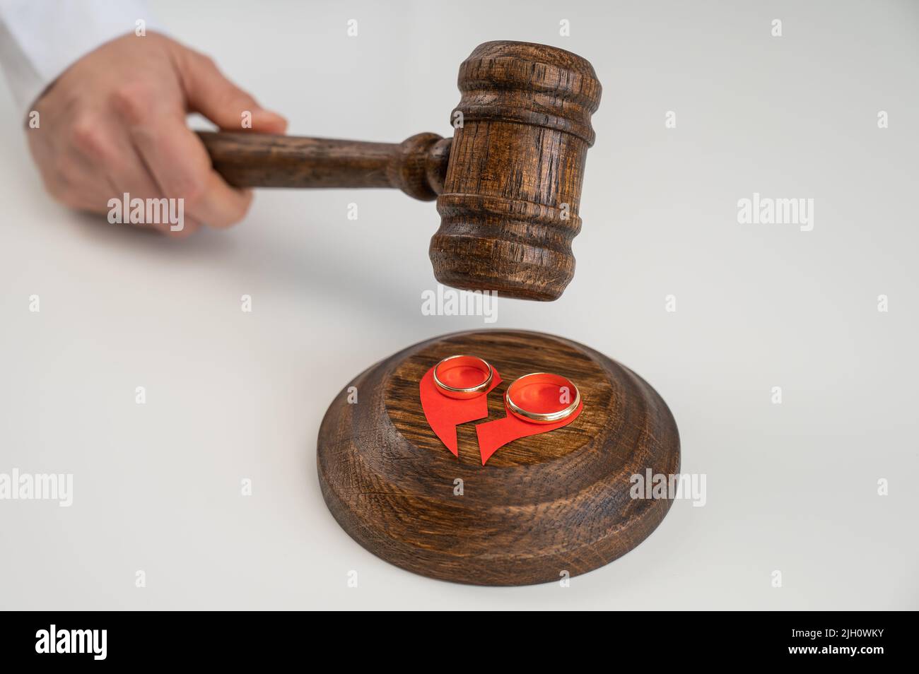 The judge hits the gavel on a broken heart and wedding rings Stock