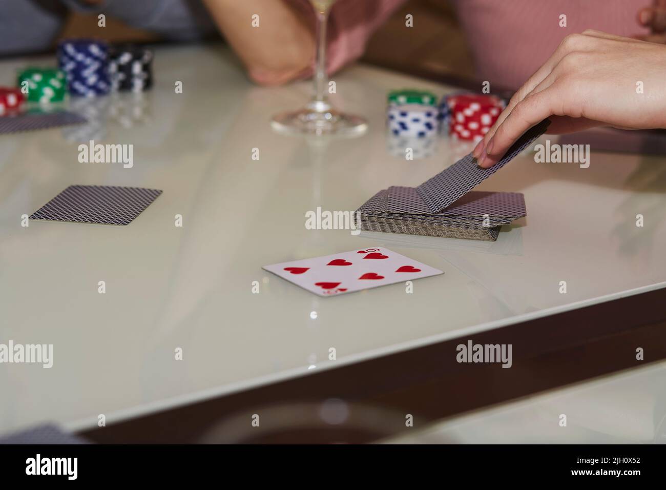 Women's hands take cards. Concept of playing poker on the table with chips and cards. Gambling concept. Enjoying the moment, digital detox with friends. Selective focus. Stock Photo