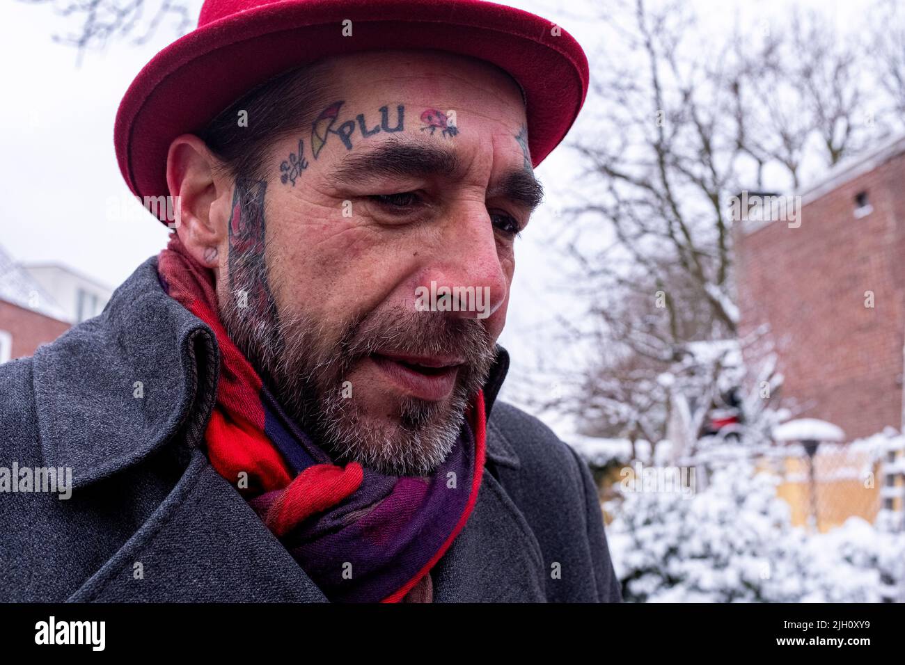 Tilburg, Netherlands. Street Portrait of a tattooed man wearing a hat during his first snow of the year stroll down town, during a Corona Crisis Lock Down. Stock Photo